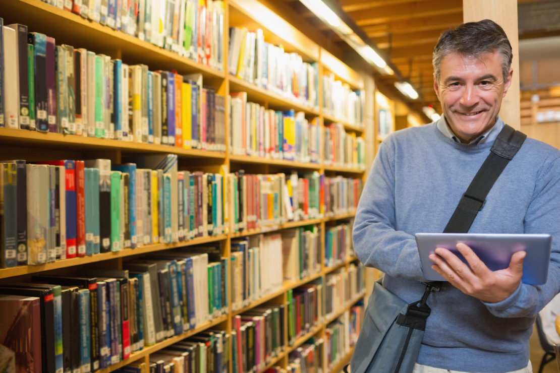 Male Learner in Library With Tablet