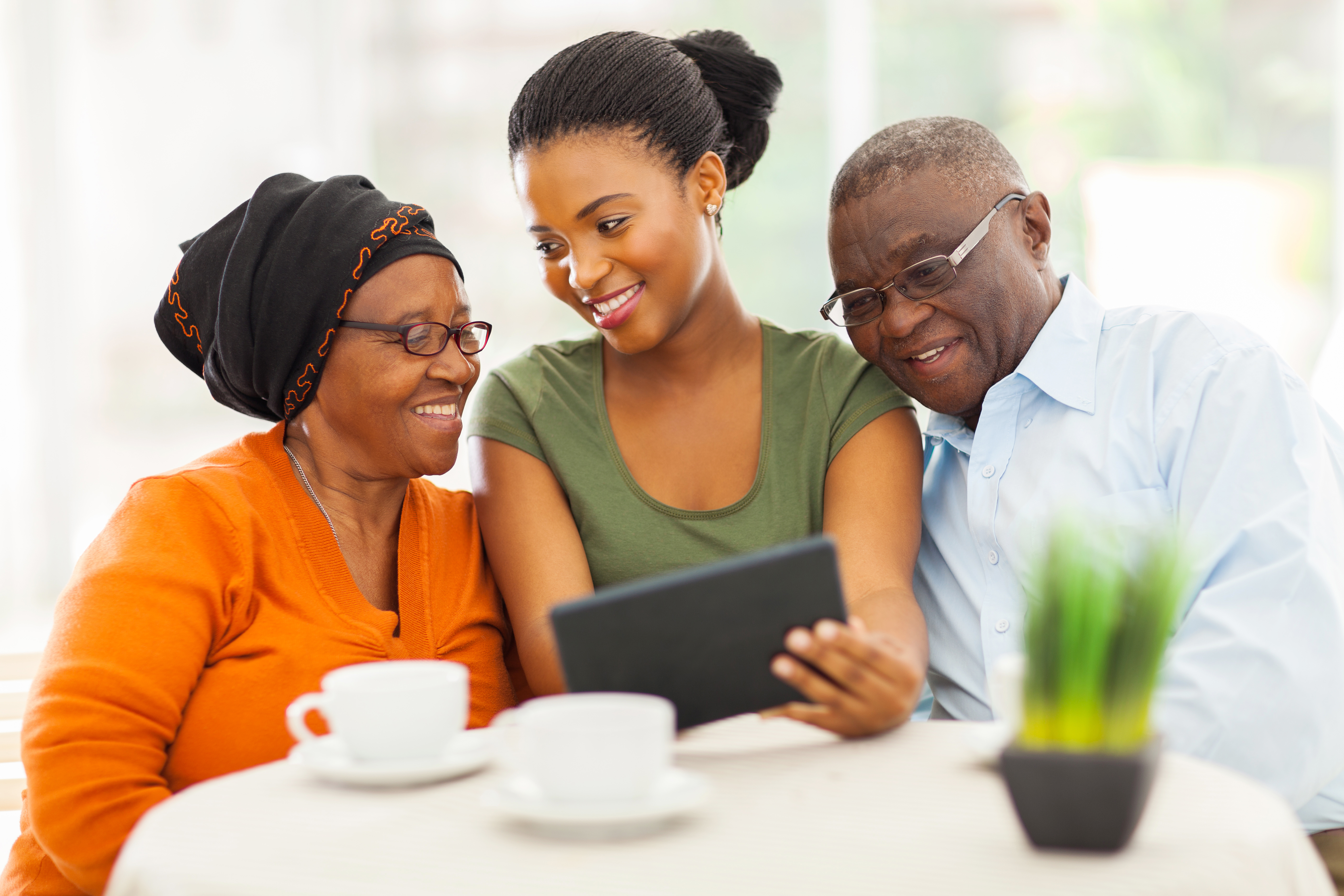 Adult Daughter Watching Streaming Video on Tablet With Her Parents